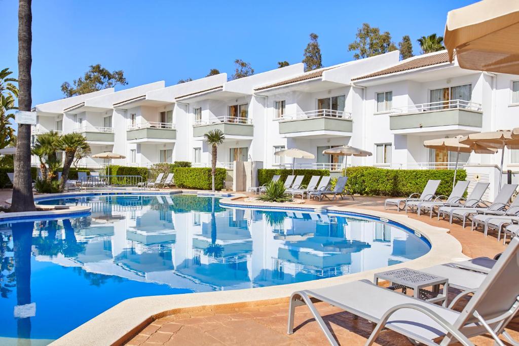 un hôtel avec une piscine et des chaises longues dans l'établissement Universal Aparthotel Elisa, à Playa de Muro