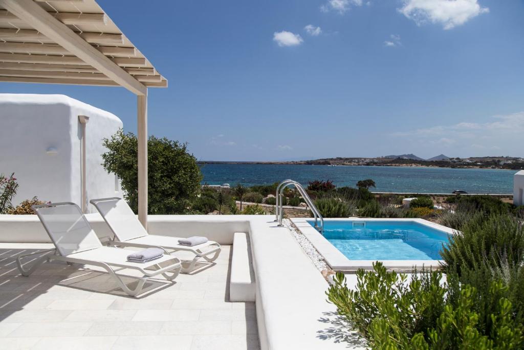 a patio with a swimming pool and chairs and the ocean at The Sand Collection Villas in Santa Maria