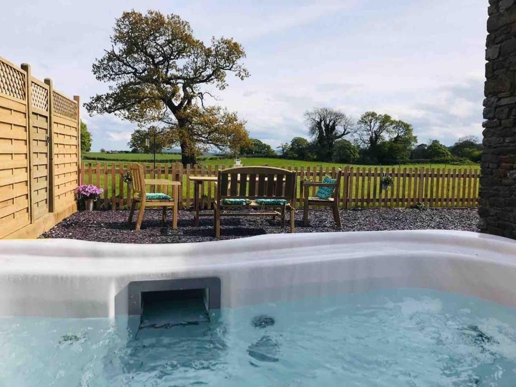 a hot tub in a yard with a table and chairs at Anvil Cottage in Mold