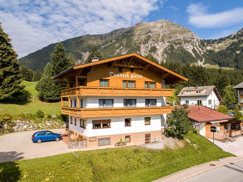 ein Gebäude mit einem Schild vor einem Berg in der Unterkunft Tanneck Garni in Berwang