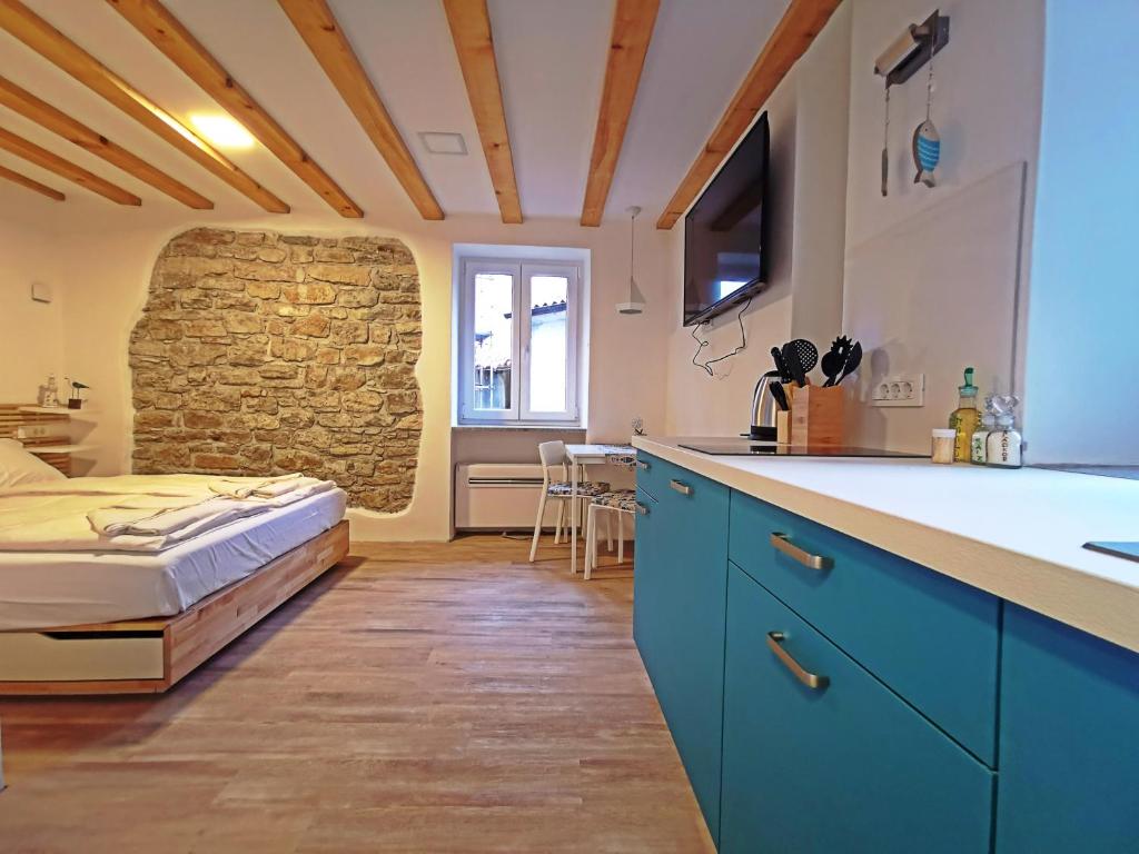 een keuken met blauwe kasten en een bed in een kamer bij Ribiška hiša - Old Piran Fisherman's House in Piran