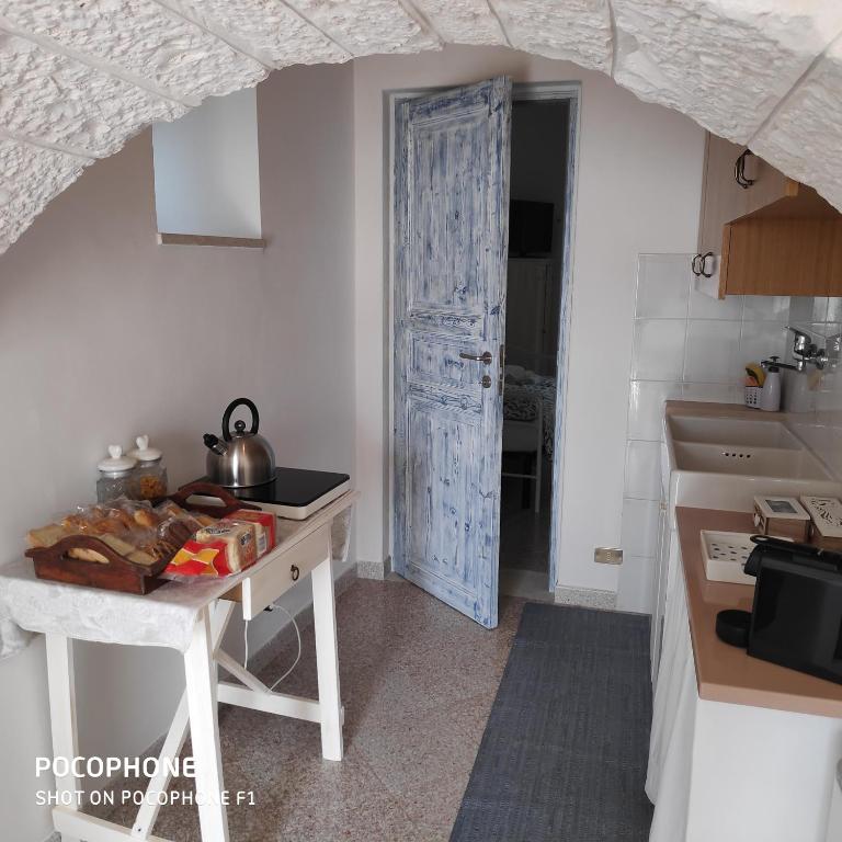 a kitchen with a table and a blue door at Dimora Sumerano in Alberobello