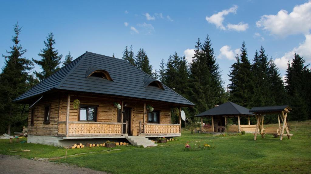 a log cabin with a porch and a gazebo at Căsuța din Povești - Vatra in Vatra Dornei