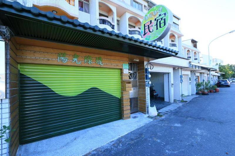 una tienda con puertas verdes de garaje al lado de un edificio en 陽光綠堤民宿 en Taitung