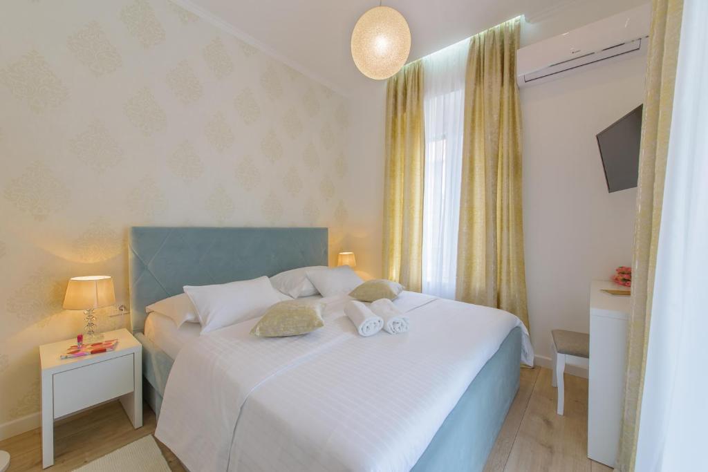 a bedroom with a white bed with two stuffed animals on it at Arcus Apartment & Arcus Room in Split