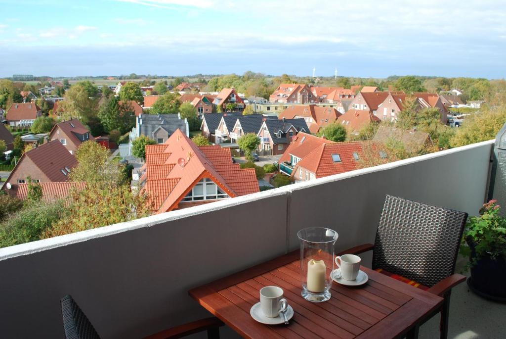 a table on a balcony with a view of a city at Ferienwohnung Sonnenschein mit Pool in Wangerland
