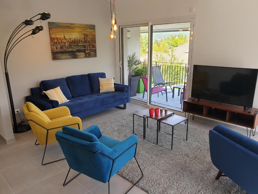 een woonkamer met een blauwe bank en stoelen en een tv bij Appartement Lac in Sévrier