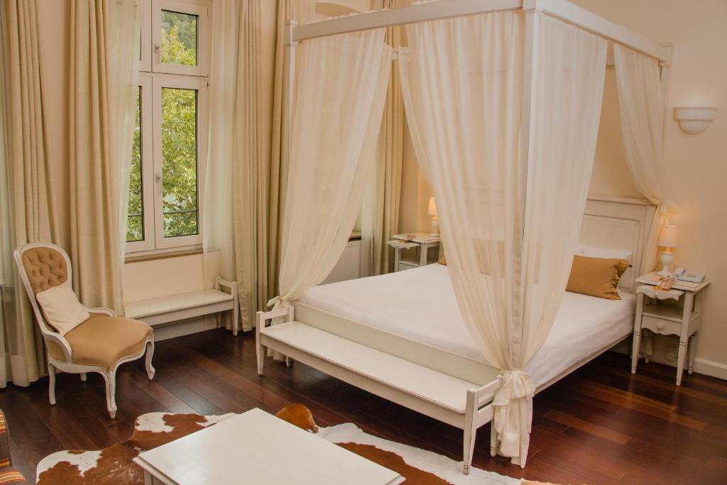 a bedroom with a canopy bed and a chair at Hotel Villa Marstall in Heidelberg