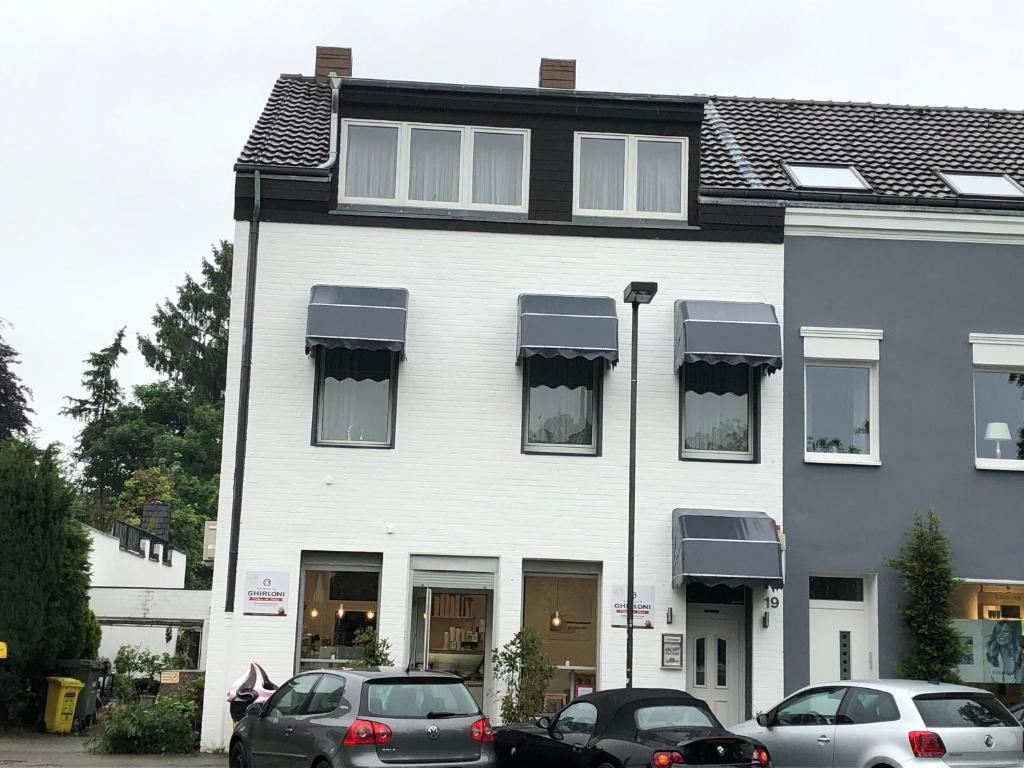 un edificio blanco con coches estacionados frente a él en Pension Pagalies, en Düsseldorf