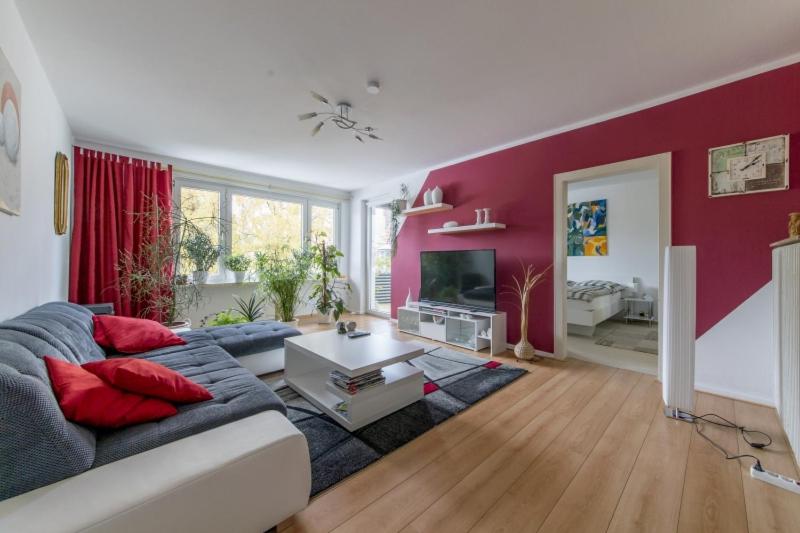 sala de estar con sofá y pared roja en Private Apartment, en Hannover