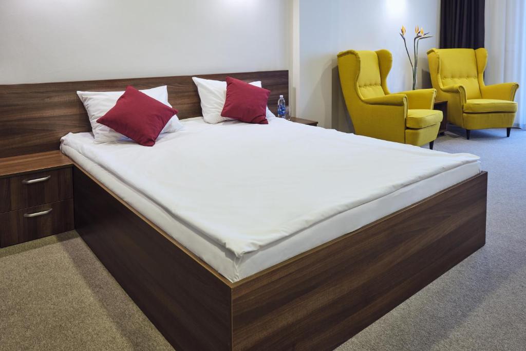 ein großes Bett in einem Zimmer mit zwei gelben Stühlen in der Unterkunft Boca Boutique Hotel in Timişoara
