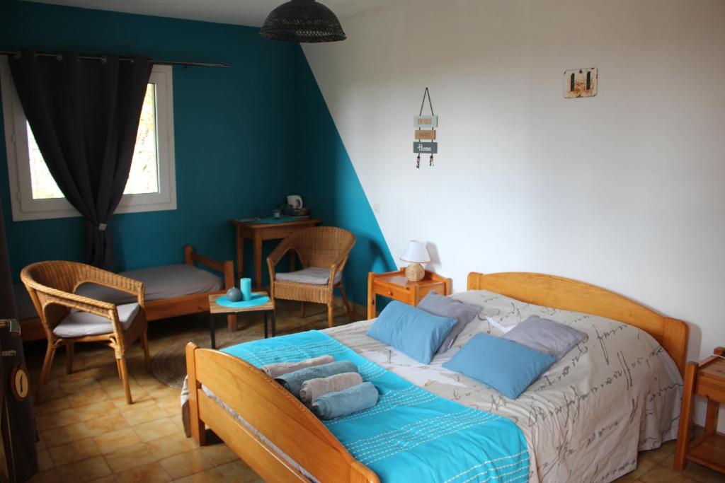 Schlafzimmer mit einem Bett mit blauer Bettwäsche und Stühlen in der Unterkunft Chambre d'hote de la Fage in La Fage