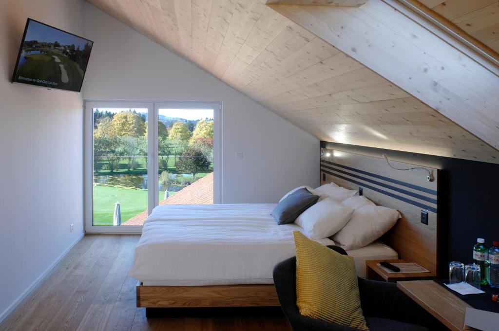 a bedroom with a large bed and a large window at Hôtel Golf-Club Les Bois in Les Bois