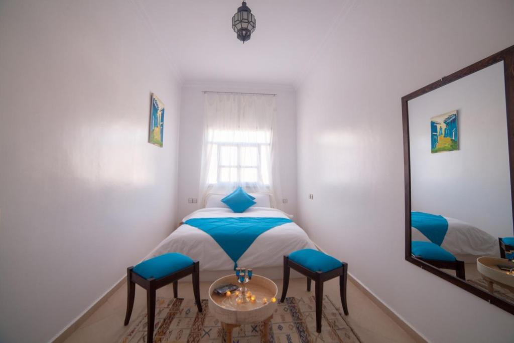 - une chambre avec un lit avec deux tabourets et un miroir dans l'établissement Bio Beldi HOME, à Tafraout