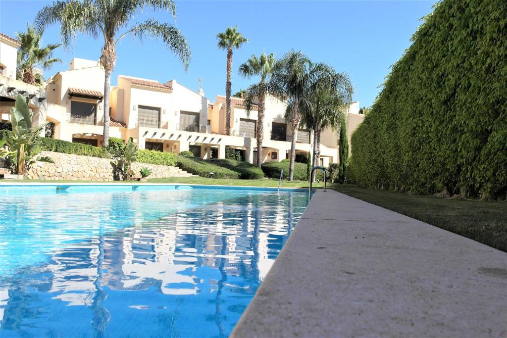 a swimming pool in front of a house with palm trees at Townhouse overlooking the pool in San Javier