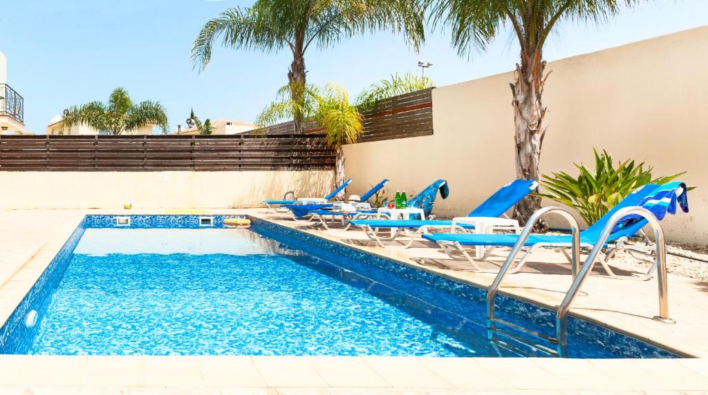een zwembad met blauwe stoelen en een zwembad bij Andina villa close to the sea in Protaras