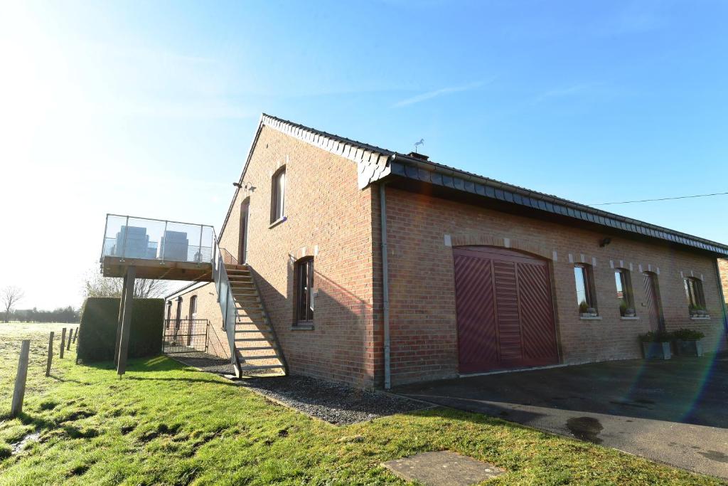 a brick building with a staircase next to a field at Le 42 in Durbuy