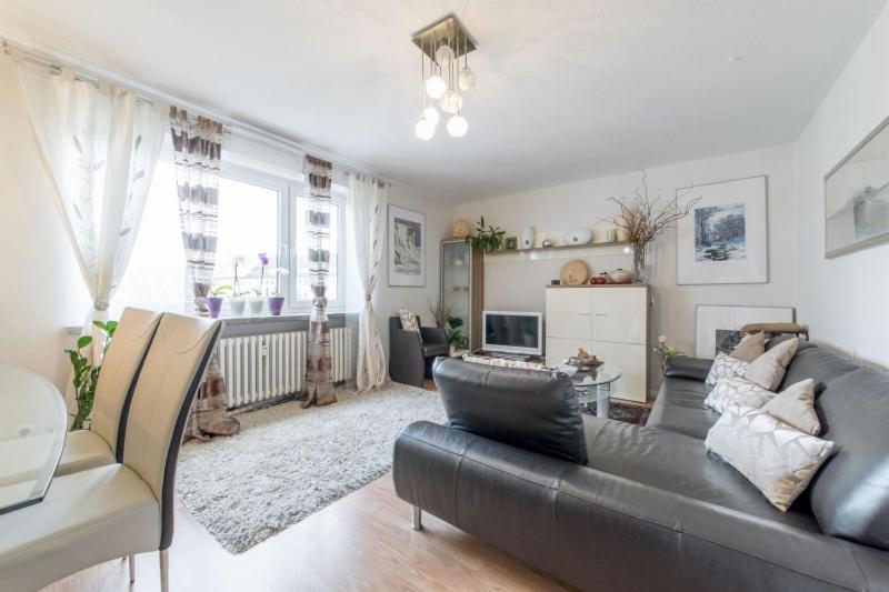 a living room with a black leather couch and a table at Private Apartment in Hannover