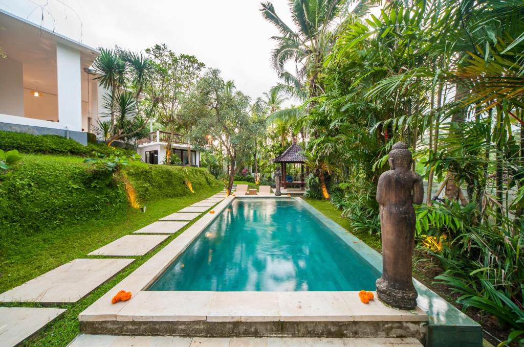 una piscina en un jardín con una fuente en Villa Cinta Ubud, en Ubud