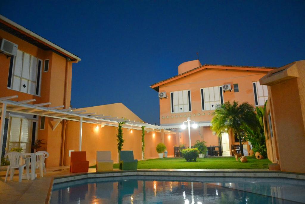 a villa with a swimming pool in front of a house at Hotel Terra do Sol in Aracaju