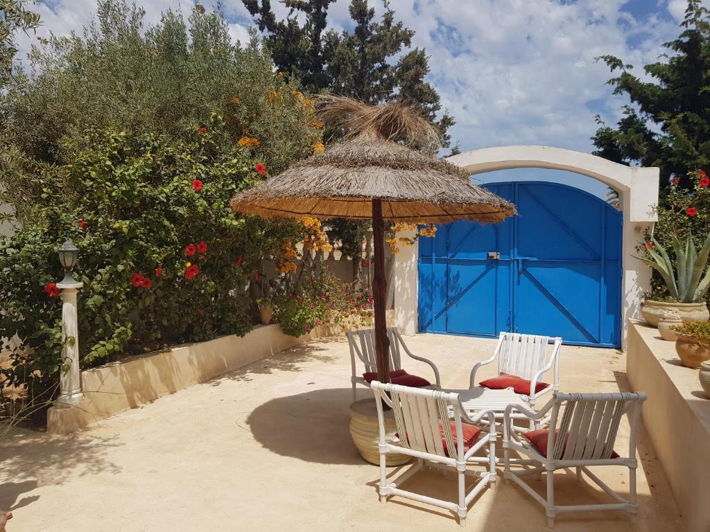two chairs and an umbrella on a patio at Menzel Churasco Djerba in Aghīr