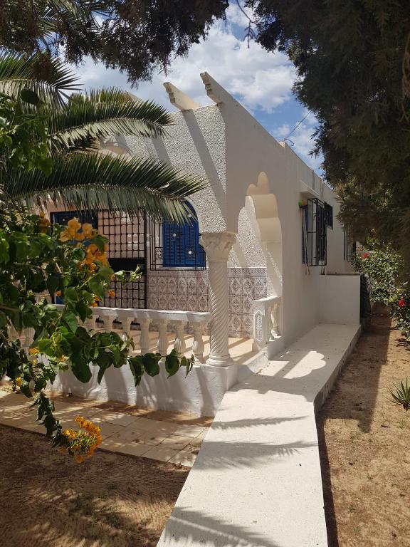 a white house with a white fence and trees at Menzel Churasco Djerba in Aghīr
