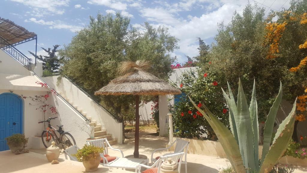 a patio with a table and chairs and an umbrella at Menzel Churasco Djerba in Aghīr