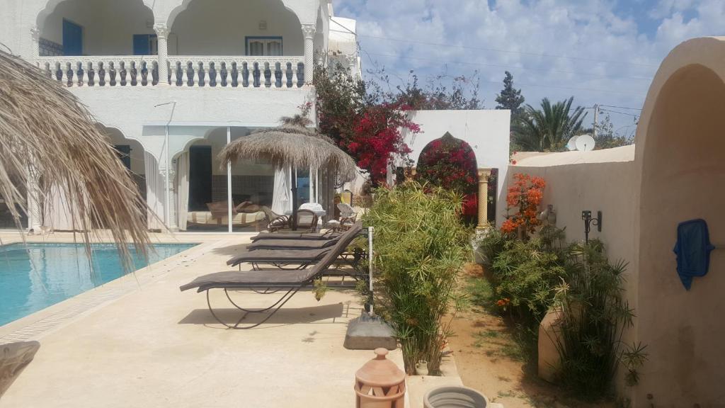 a group of benches sitting next to a swimming pool at Menzel Churasco Djerba in Aghīr