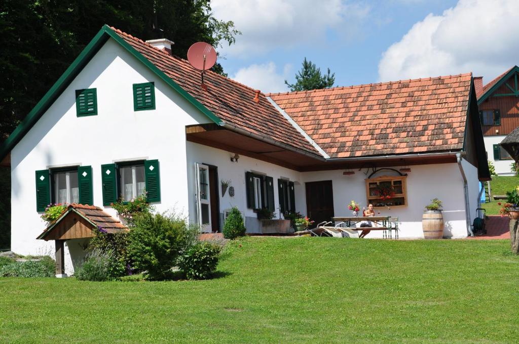 een wit huis met een rood dak en een tuin bij s´ Kellerstöckl in Loipersdorf bei Fürstenfeld