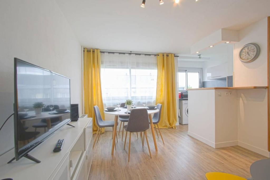 sala de estar con mesa de comedor y TV en APPARTEMENT MODERNE A CAEN POUR 4 PERSONNES en Caen