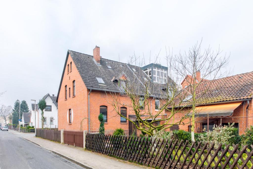 a red brick house with a fence on a street at Private Rooms in Hannover