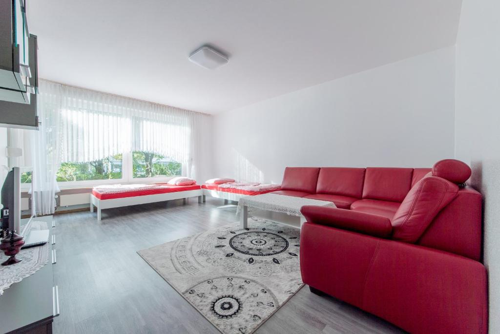 - un salon avec un canapé rouge et une table dans l'établissement Privatapartment Messe Süd, à Hanovre