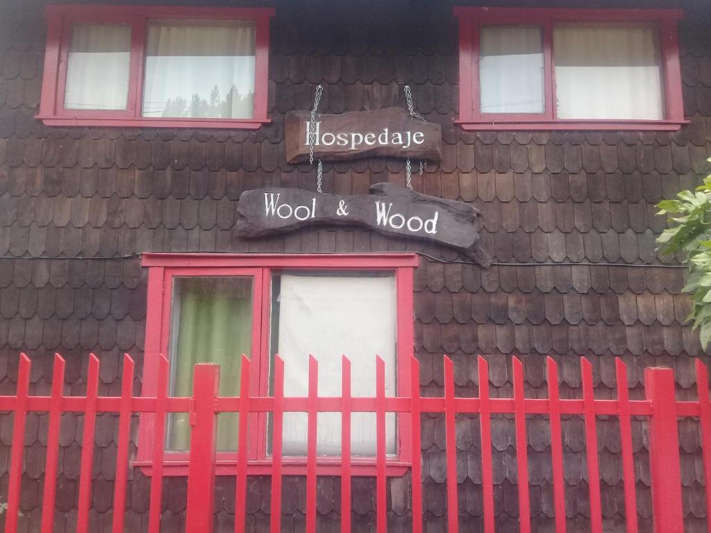 una cerca roja frente a una casa con un cartel de madera en Wool & Wood House en Puerto Varas