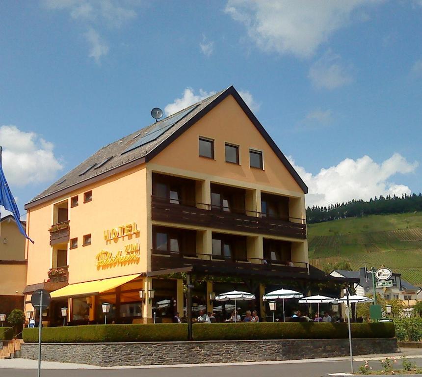 un grand bâtiment avec des parasols en face de celui-ci dans l'établissement Hotel Zum Fährturm, à Mehring