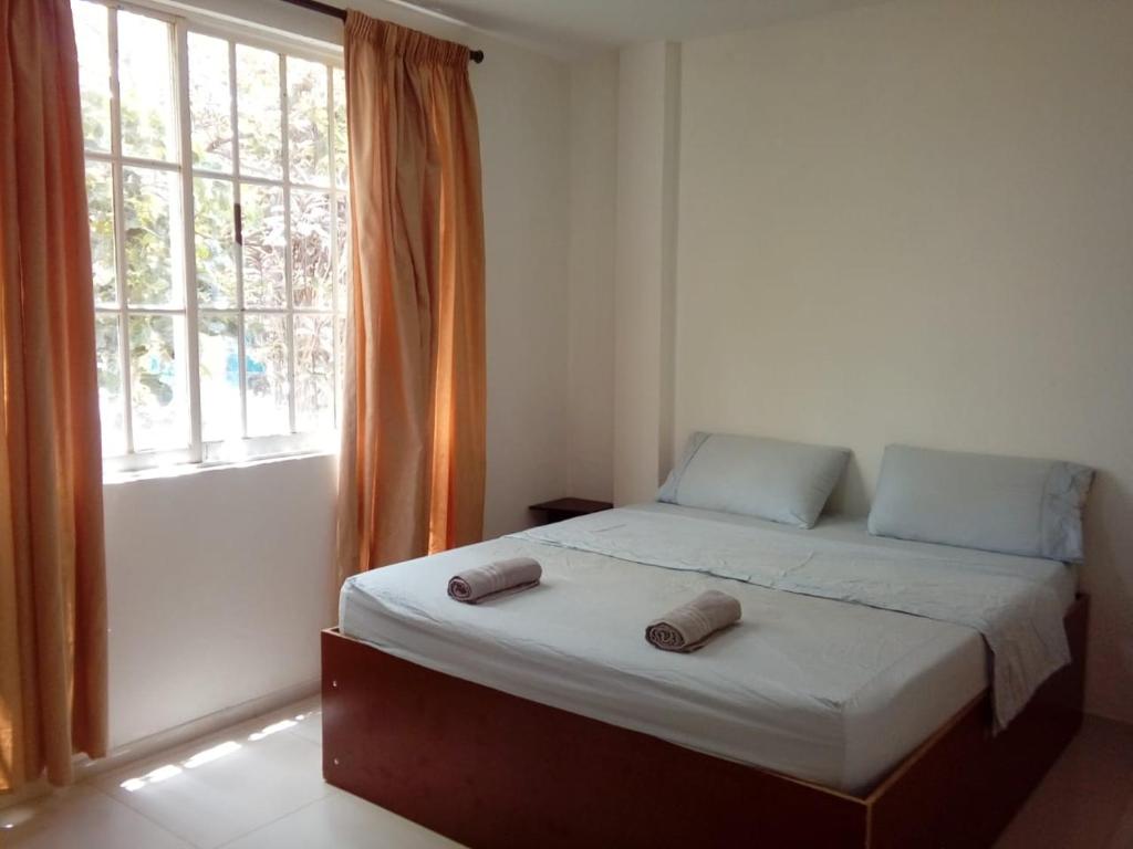 ein Schlafzimmer mit einem Bett mit zwei Hausschuhen darauf in der Unterkunft Hostal green bay in San Andrés