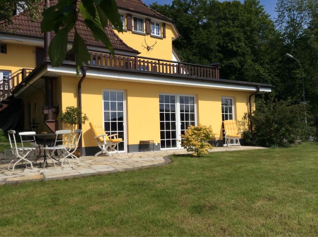 a yellow house with chairs and a table in a yard at Wollmeiner's Lodge in Arnsberg