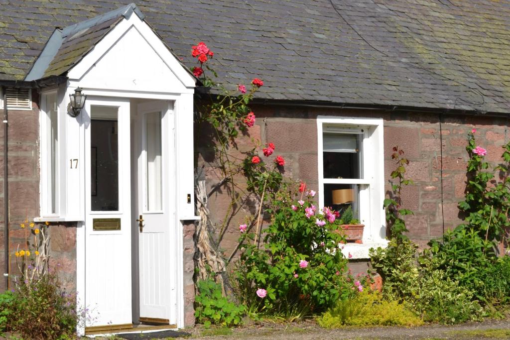a small house with a white door and flowers at Camlann in Alyth