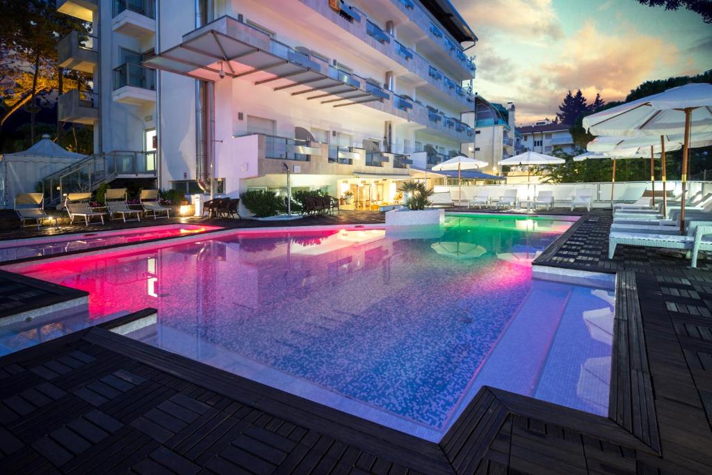 uma piscina em frente a um edifício à noite em Hotel Rex em Lignano Sabbiadoro