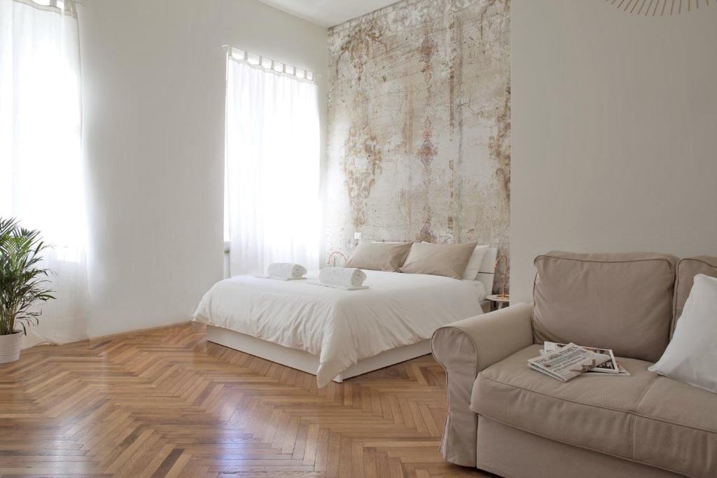 トリノにあるRapanus Suitesの白いベッドルーム(ベッド1台、ソファ付)