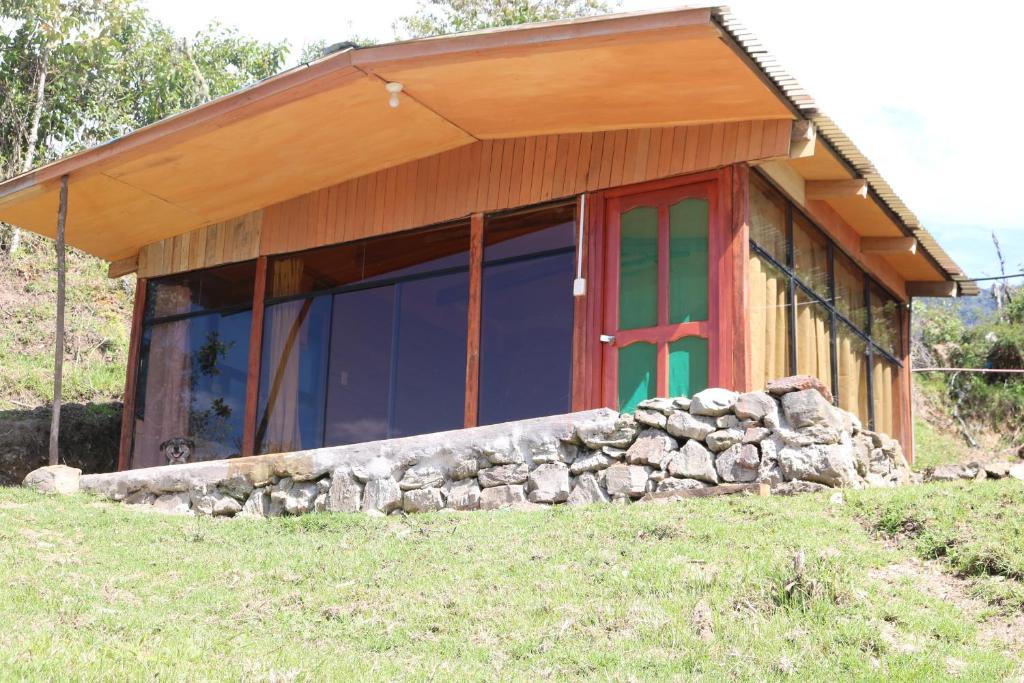 a house with a red door and a stone wall at Llactapata Lodge overlooking Machu Picchu - camping - restaurant in Salcantay