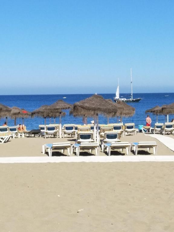 a group of chairs and umbrellas on a beach at Fuengirola Holidays Sun & Beach in Fuengirola