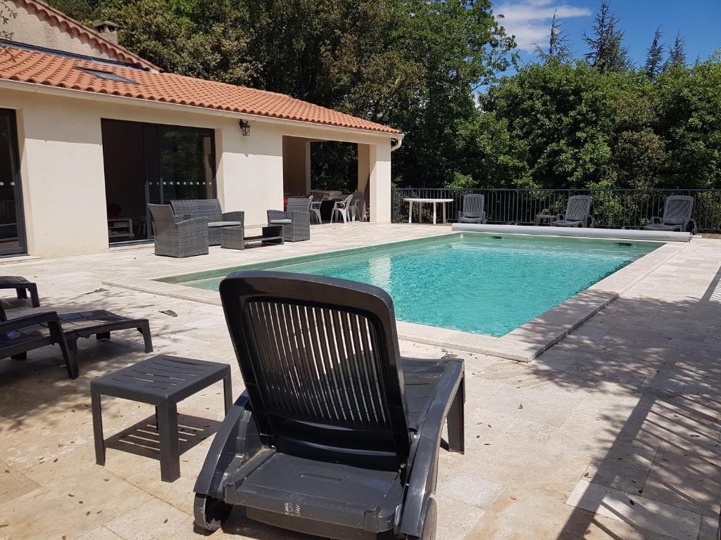 uma cadeira preta sentada ao lado de uma piscina em La Casita villa avec piscine prés d'Uzes em Saint-Laurent-la-Vernède