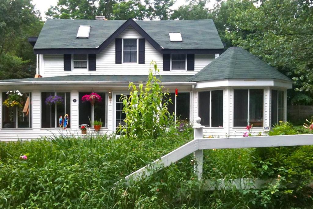 a white house with a porch and flowers in the yard at Play All Day - Sleep By The Stream at Night - Swimming Hole in Palenville