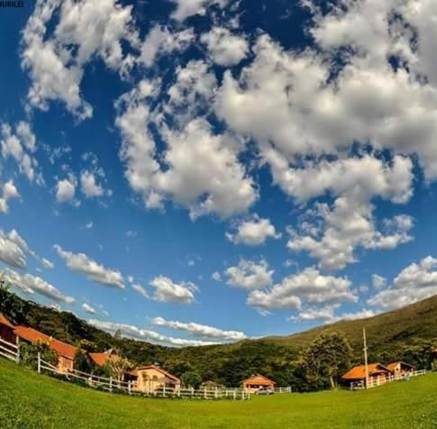 un campo con una recinzione e un cielo con nuvole di Recanto JF da Serra a São Thomé das Letras