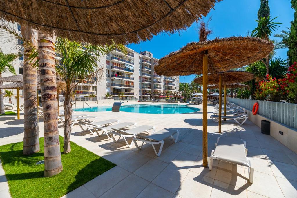 a resort with a swimming pool with chairs and umbrellas at Rentalmar Navarra family suites in Salou