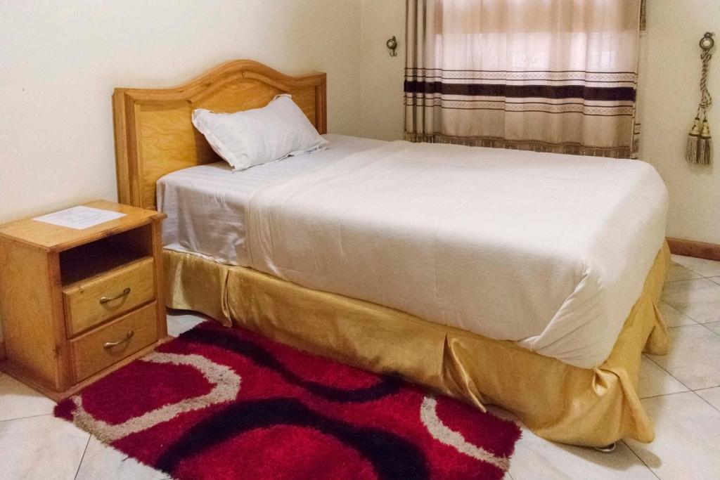 a bedroom with a bed and a nightstand and a bed sidx sidx at Capricon Executive Hotel Kabale in Kabale