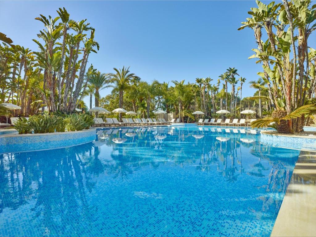 uma grande piscina com palmeiras e guarda-sóis em Ria Park Hotel & Spa no Vale do Lobo