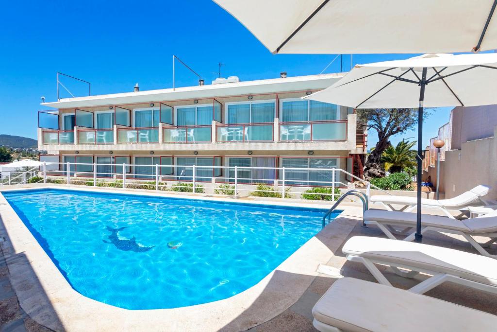 a swimming pool with an umbrella and a building at Hostal Molins Park in Ibiza Town