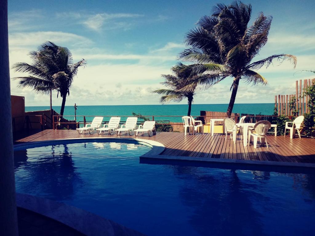 - une piscine avec des chaises et une vue sur l'océan dans l'établissement Atlântico Flat - Apt 108, à Natal