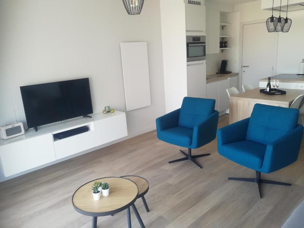 a living room with two blue chairs and a tv at Zeebriesje in Oostduinkerke